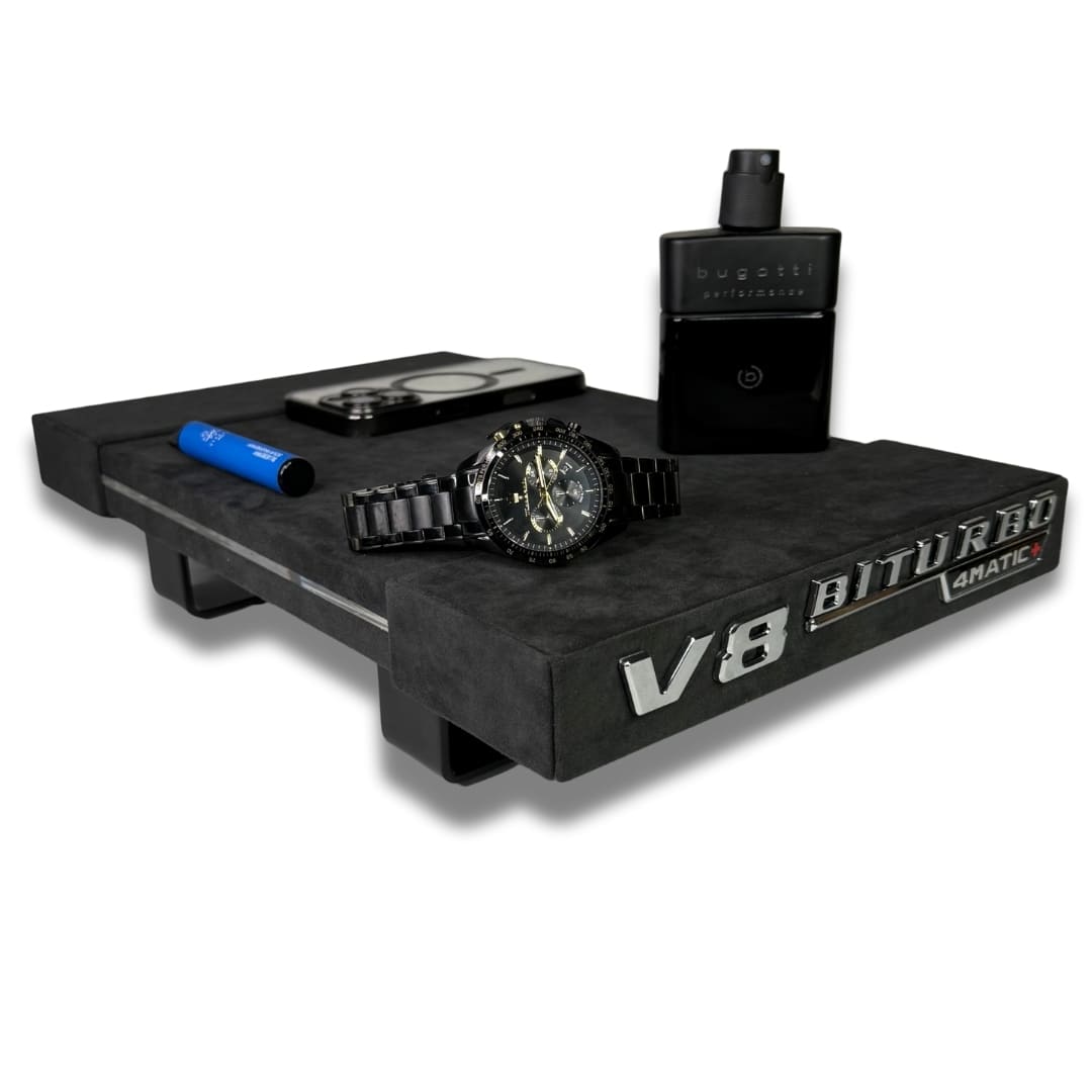 Schwarzes Alcantara Brett mit V8 Biturbo Schriftzug und abgelegten Gegenständen